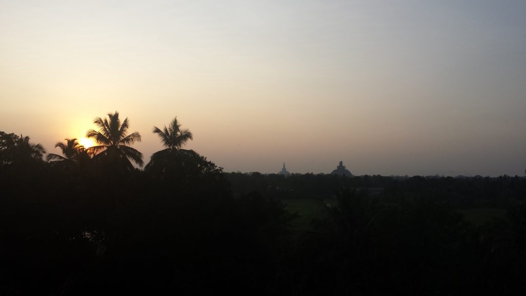 Solnedgang med stupaer i baggrunden